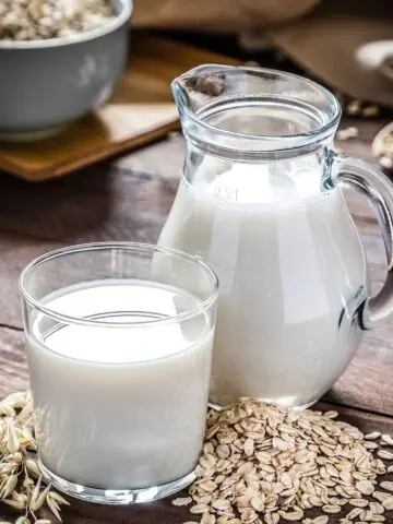 Oat milk in glass and jug.