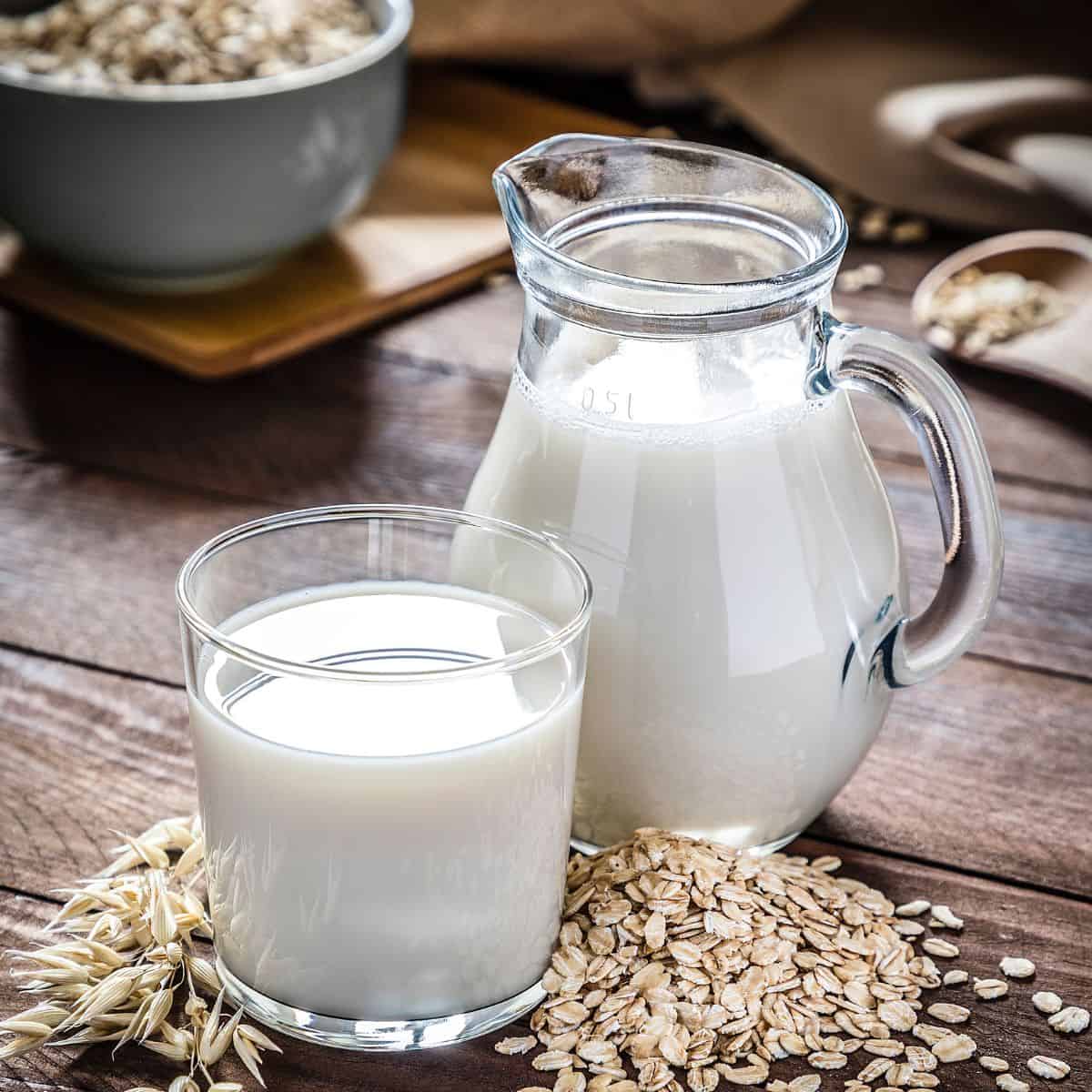 Oat milk in glass and jug.