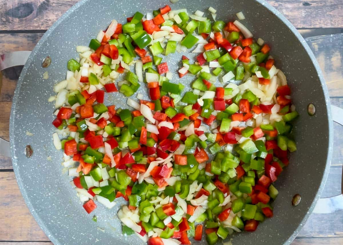 Diced red and green peppers with diced onions in Dutch oven.