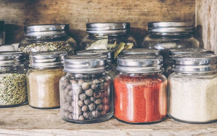 assorted spices in jars in wood cabinet