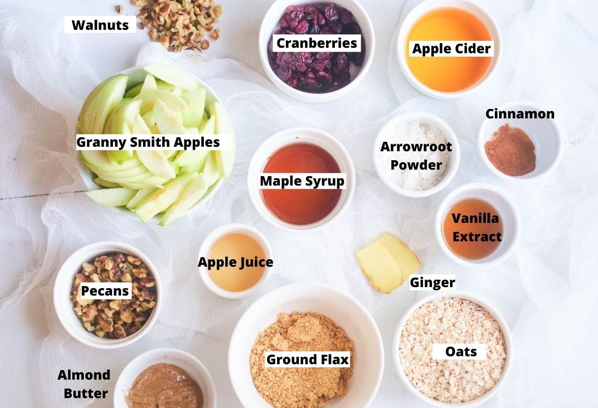 Vegan apple crisp ingredients: apples, oats, nuts, cranberries, vanilla, maple syrup, flax, almond butter, ginger, apple juice, apple cider, arrowroot powder.