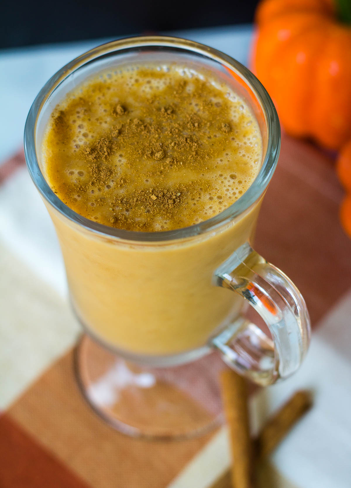 Vegan pumpkin smoothie in glass cup with cinnamon on top.