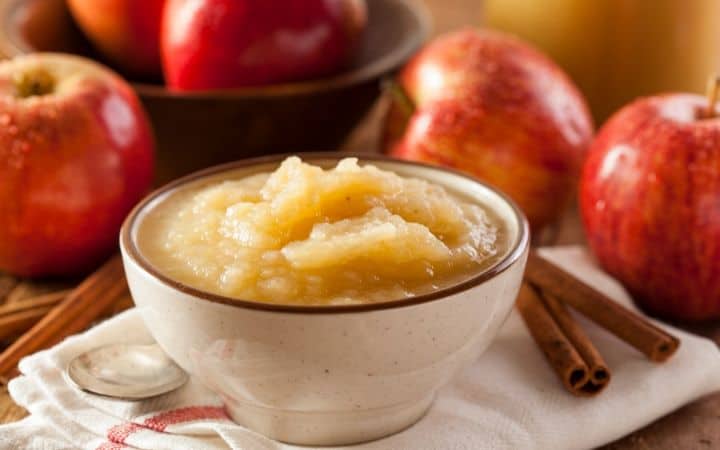 applesauce surrounded by apples and cinnamon sticks