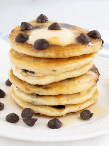 Stack of vegan chocolate chip pancakes on white plate.