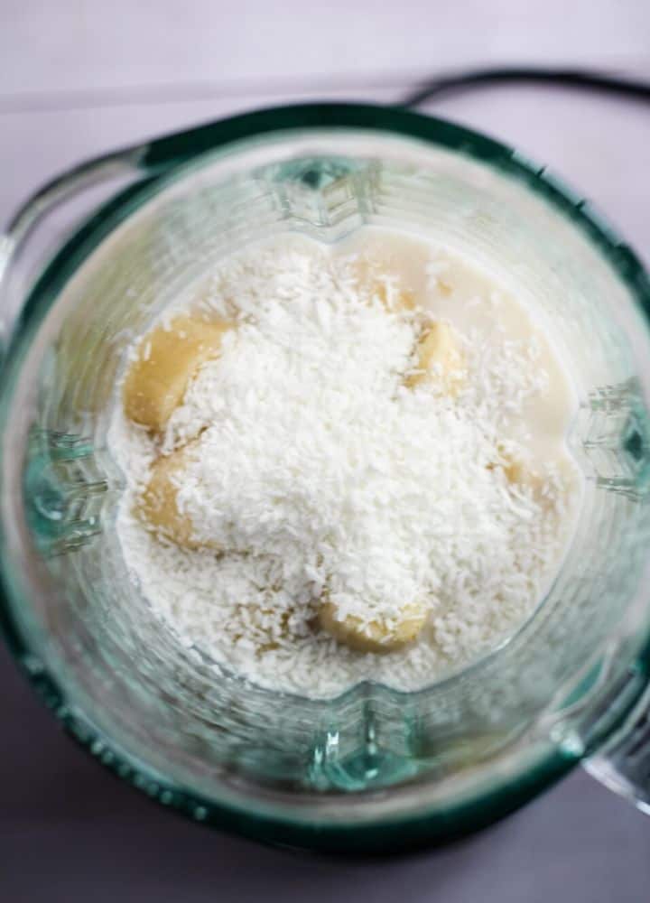 Almond milk, banana, and coconut flakes in blender.