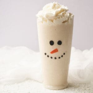 Snowman Christmas smoothie topped with whipped cream in tall glass.