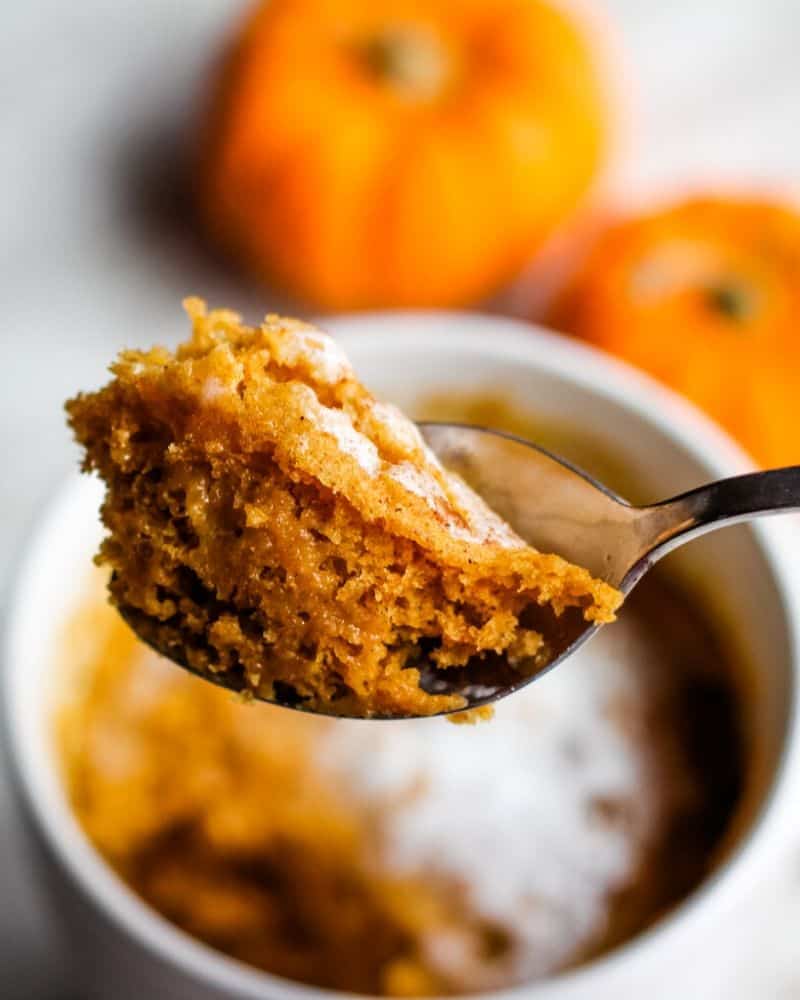 Spoon holding pumpkin mug cake.