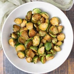 Bowl of soy glazed brussels sprouts in white serving bowl.