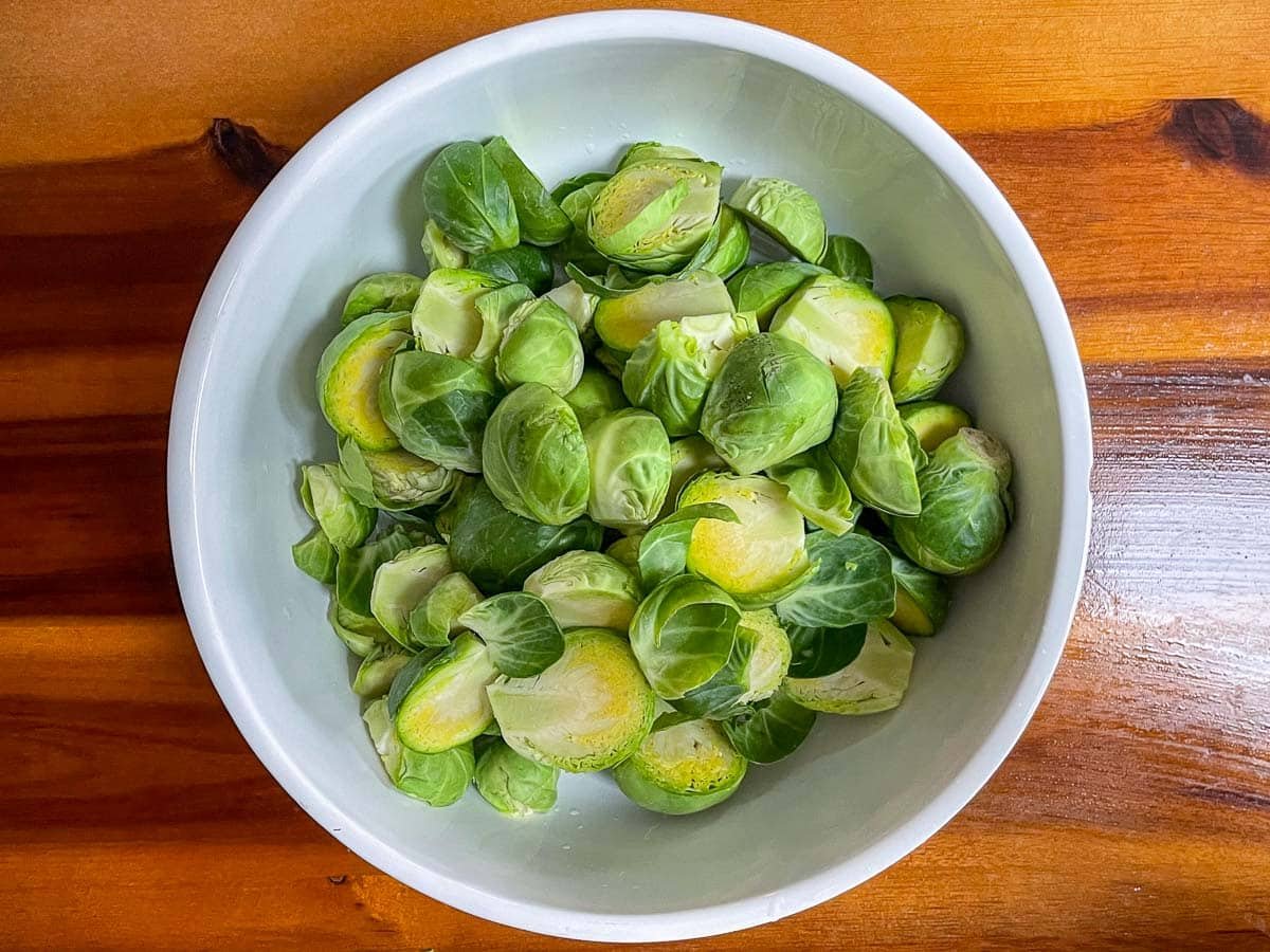 Cut and trimmed brussels sprouts in a white bowl.