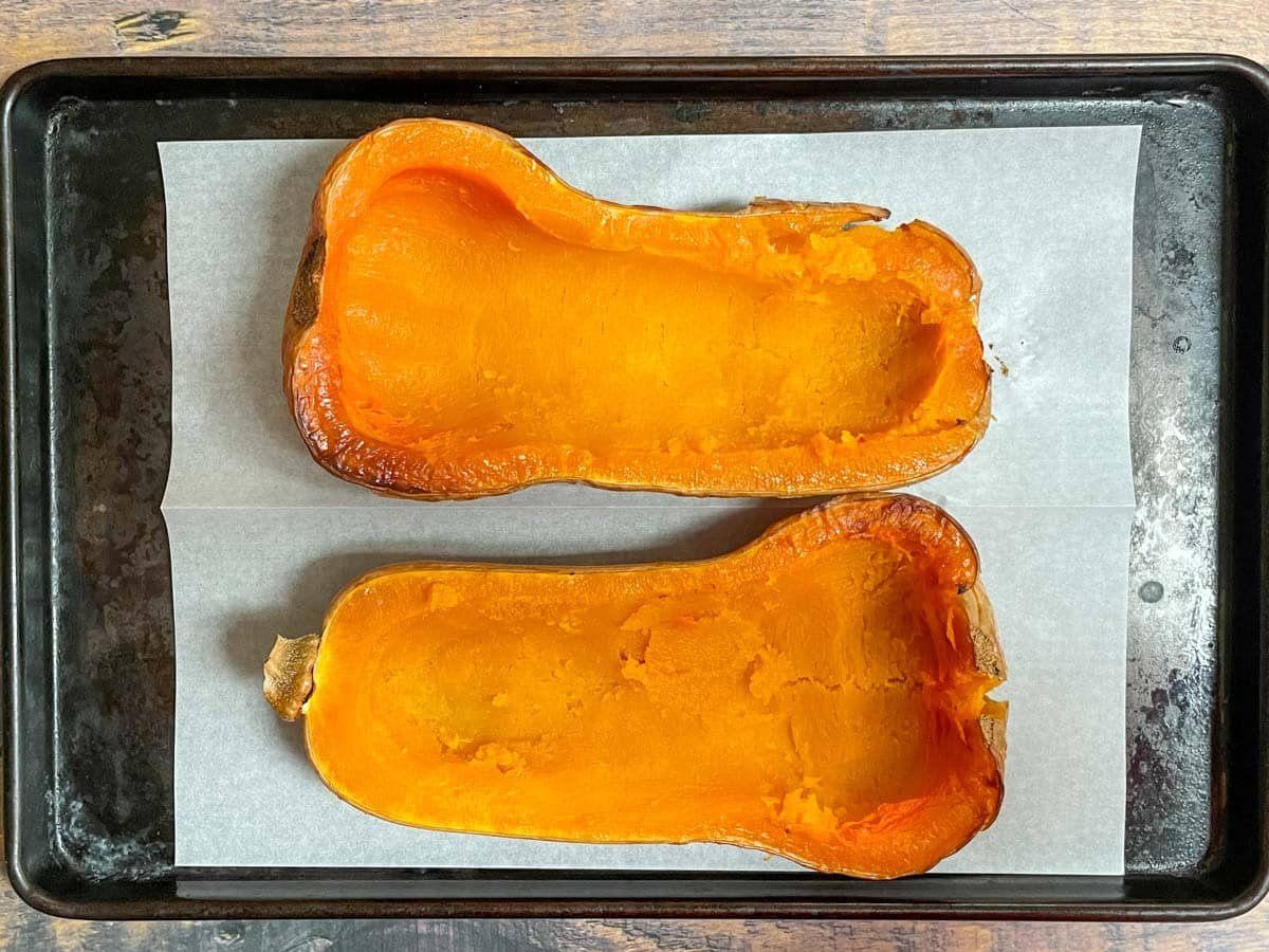 Cooked butternut squash halves with center scooped out.