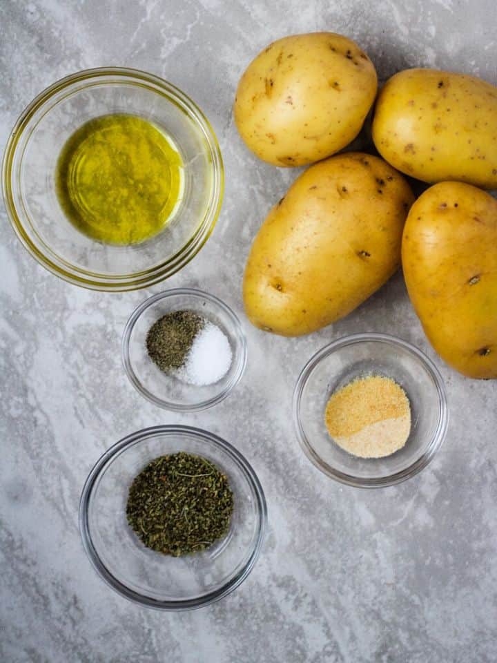 yukon gold potatoes, olive oil, salt and pepper, herbs, and spices in glass bowls