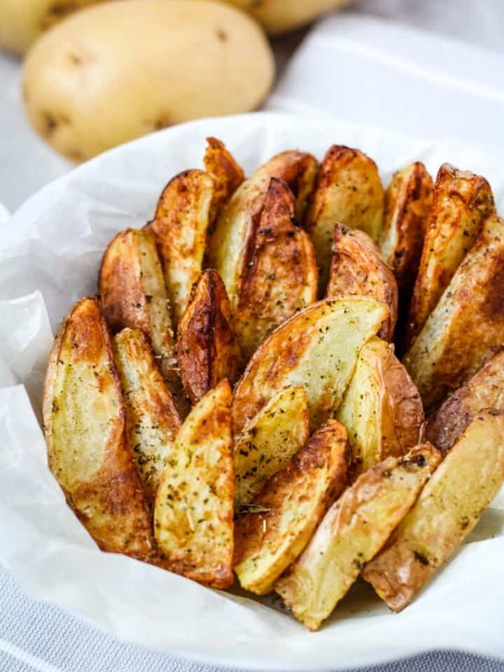 air fryer potato wedges in bowl wrapped with parchment paper