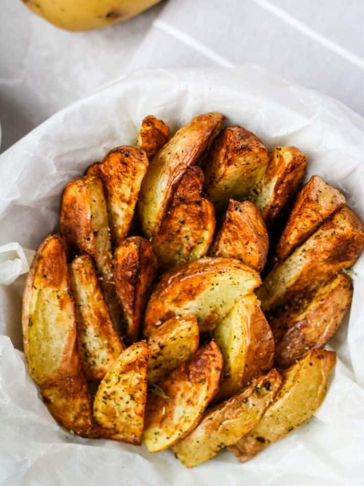 air fryer potato wedges in bowl with white paper