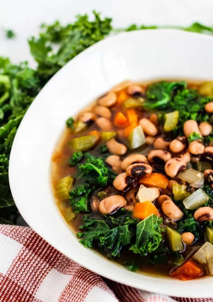 black eyed pea soup with kale in white bowl