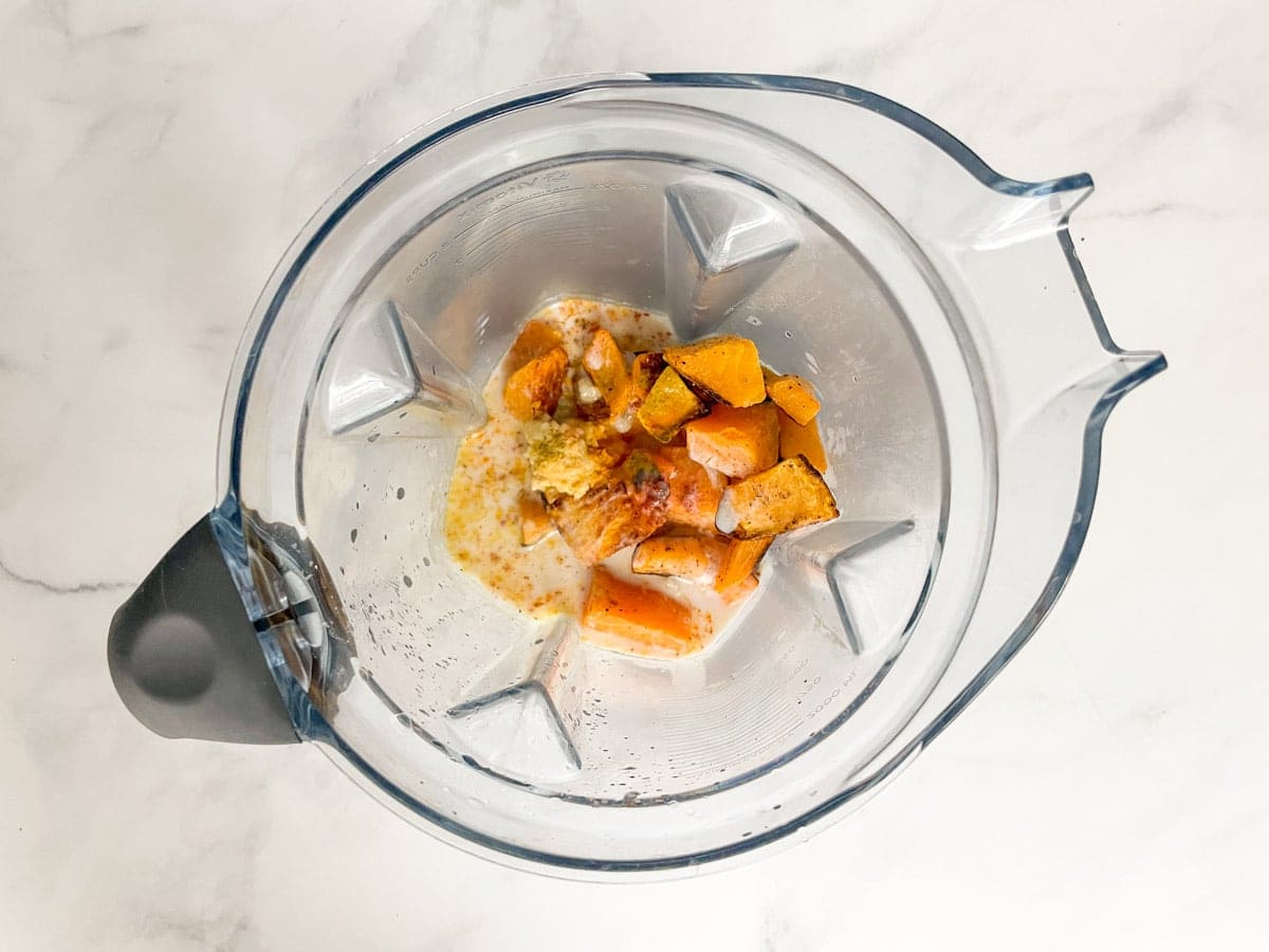 Cooked and cubed butternut squash, spices, and almond milk in blender.