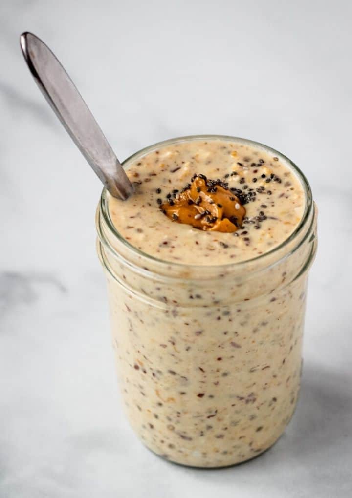 creamy oats topped with peanut butter and chia seeds in a mason jar with a spoon