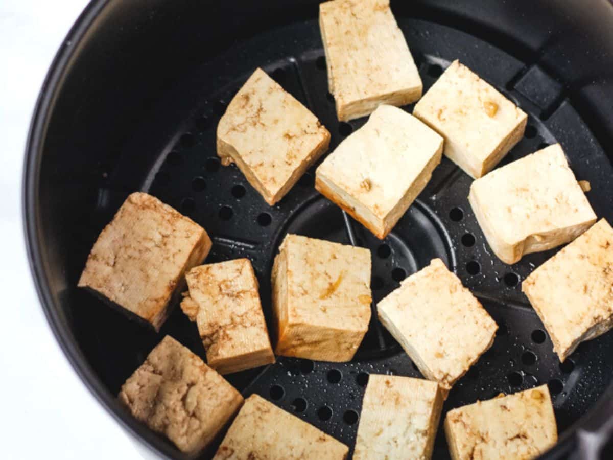 Tofu cubes in air fryer basket.