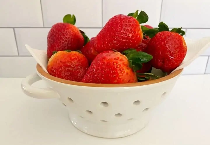 Strawberries in colander with paper towel.
