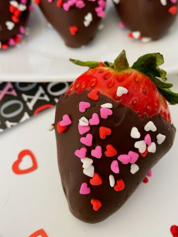 Chocolate covered strawberries with heart sprinkles.