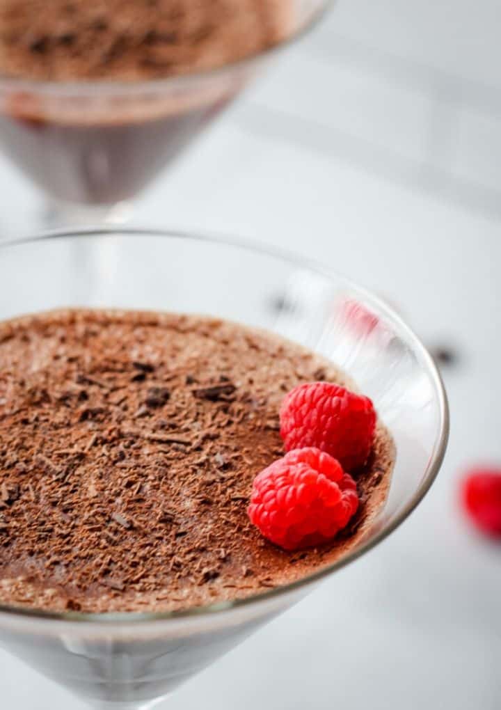 close up of aquafaba chocolate mousse topped with two raspberries in a martini glass