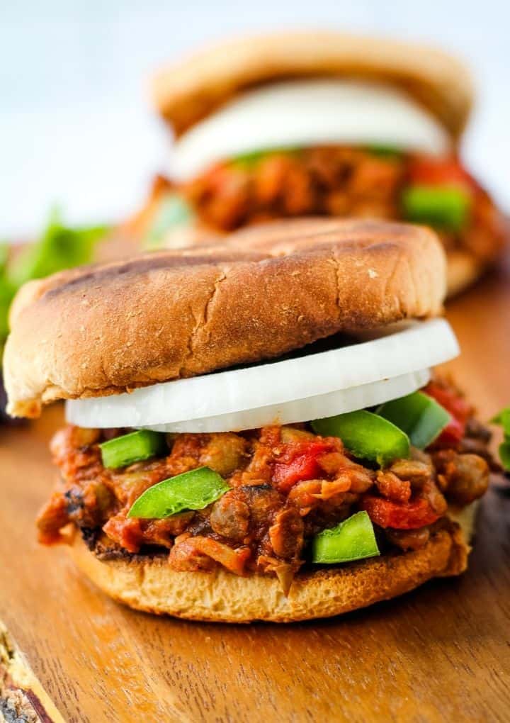 vegan sloppy joe on wood serving tray served with sliced onion and green pepper