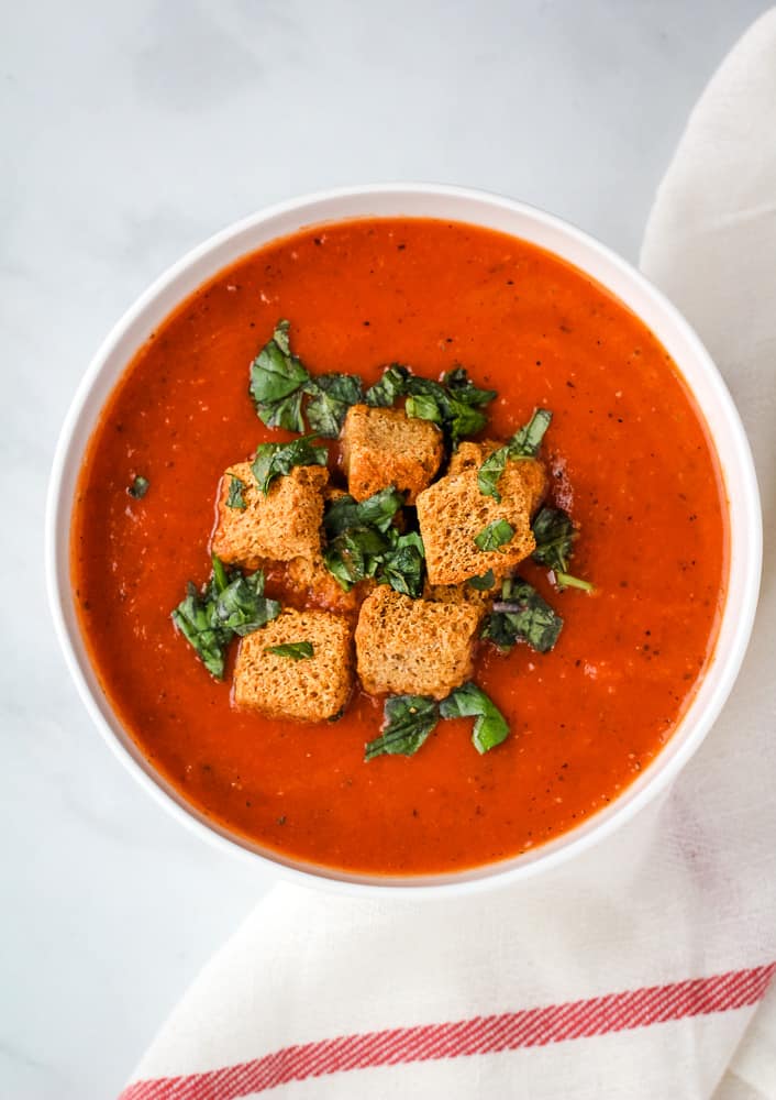 Vegan tomato soup topped with croutons and basil.