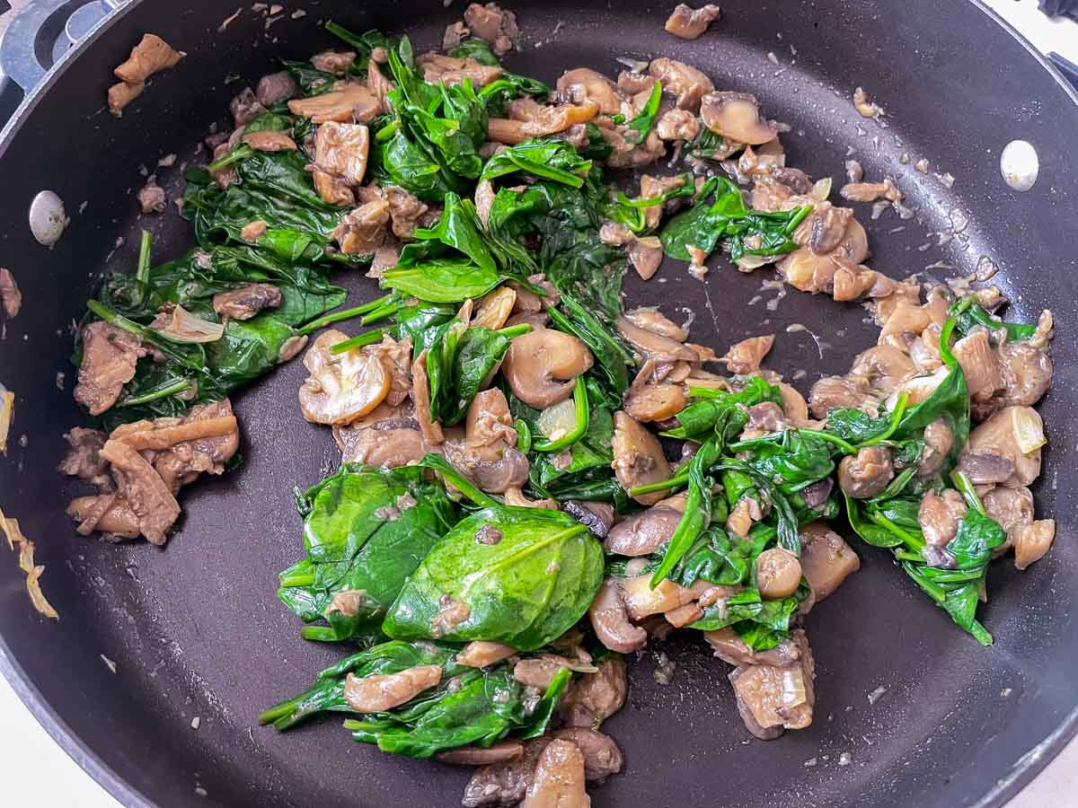 Mushrooms and spinach in saute pan.