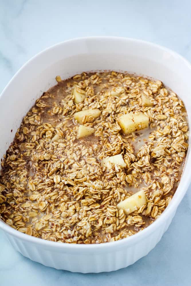 Oats, apples and almond milk in baking dish.