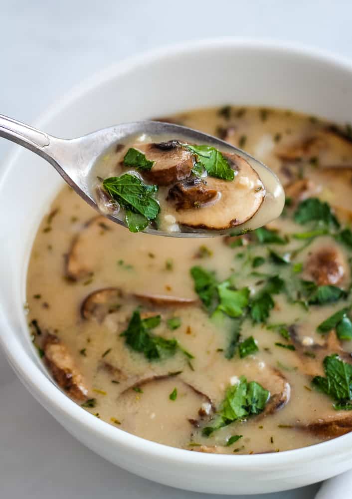 Mushroom soup in bowl topped with fresh herbs.