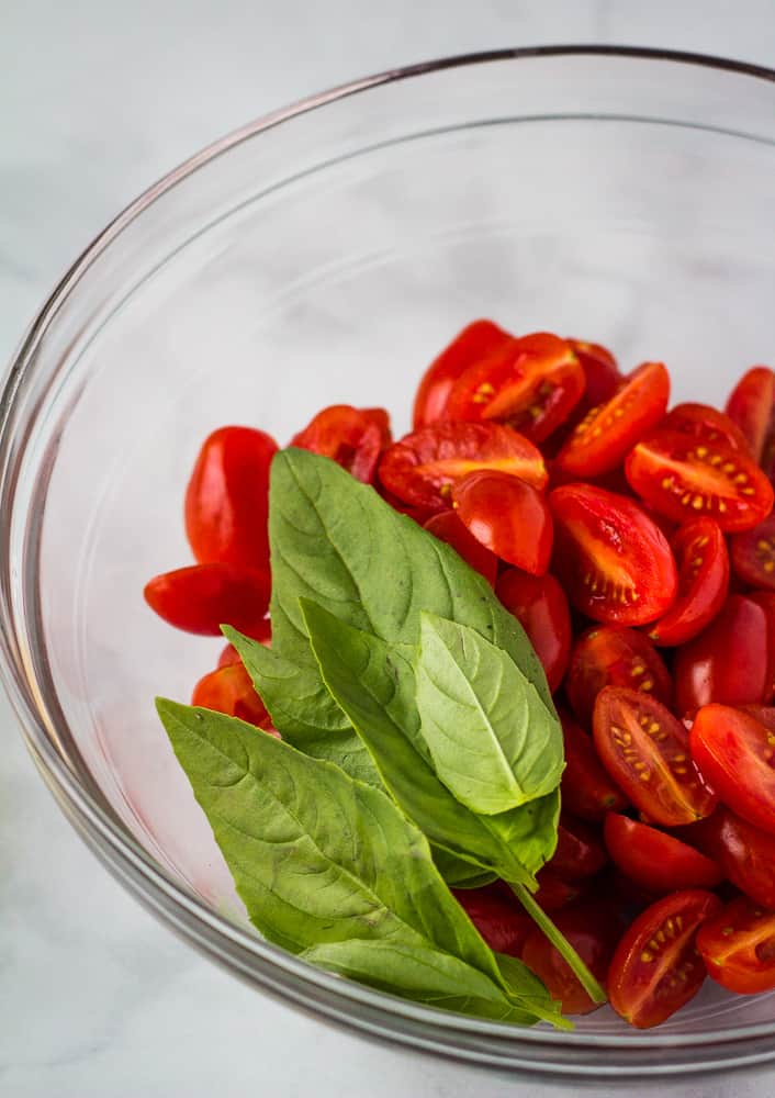 cherry tomatoes and basil in glass bowl