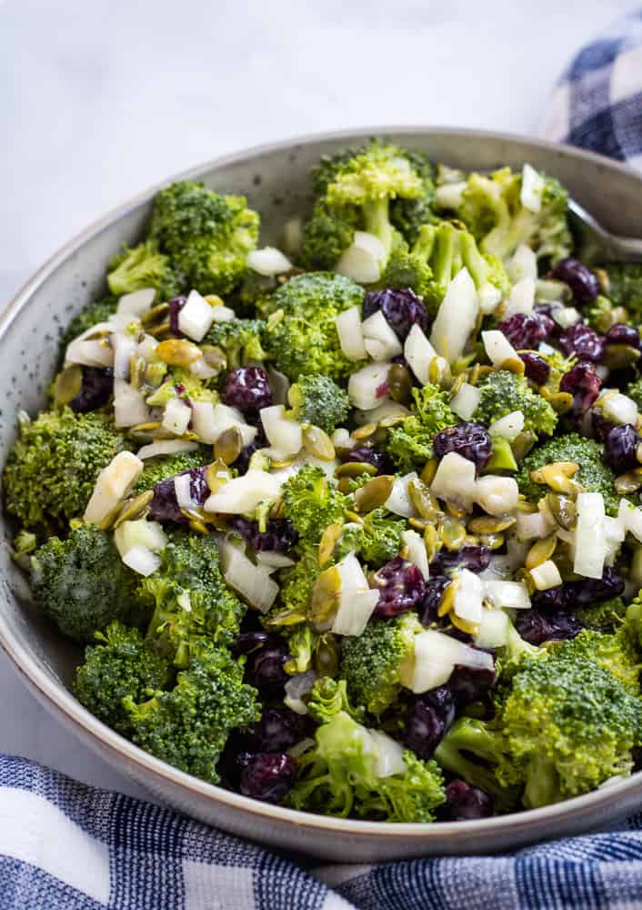 broccoli salad topped with cranberries onion, and pumpkin seeds