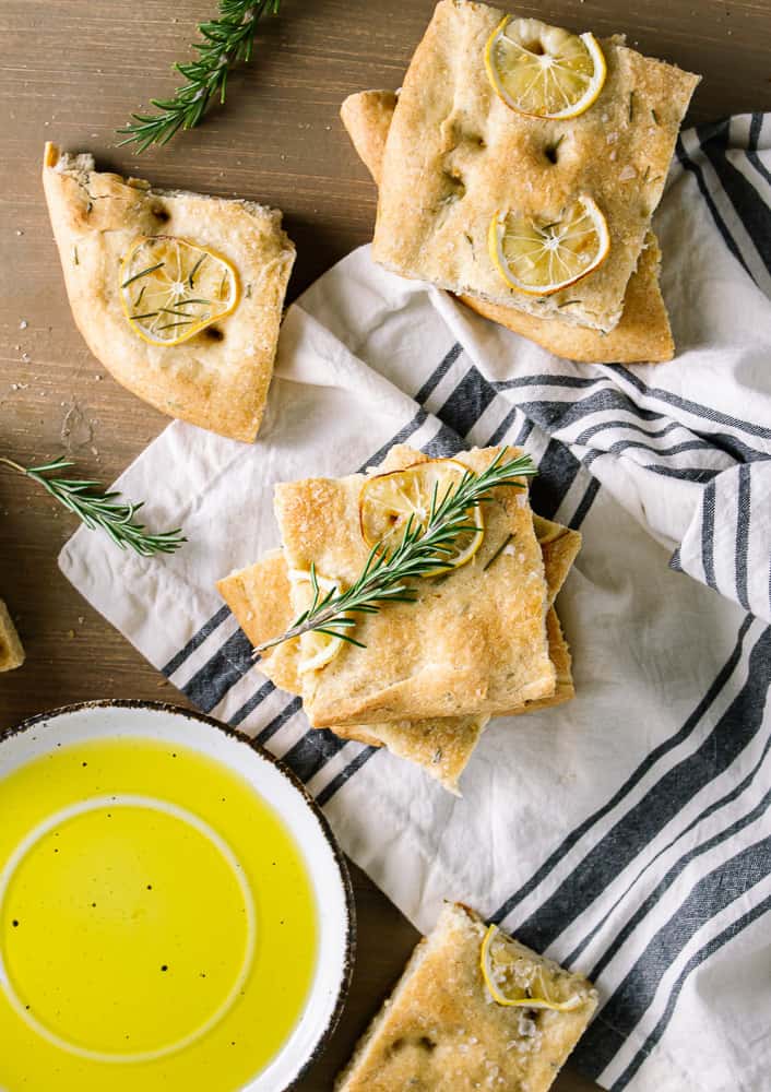 olive oil, rosemary and bread on dish towel