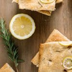 Slices of focaccia bread with sprig of rosemary and slice of lemon.