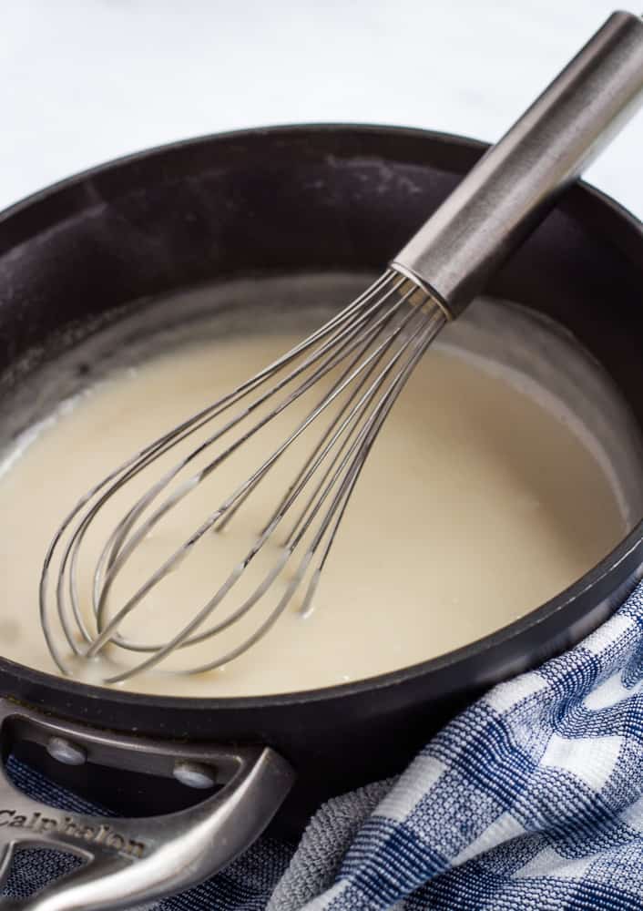 Coconut milk in pan with whisk.