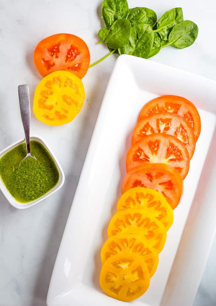 sliced heirloom tomatoes with basil sauce on the side