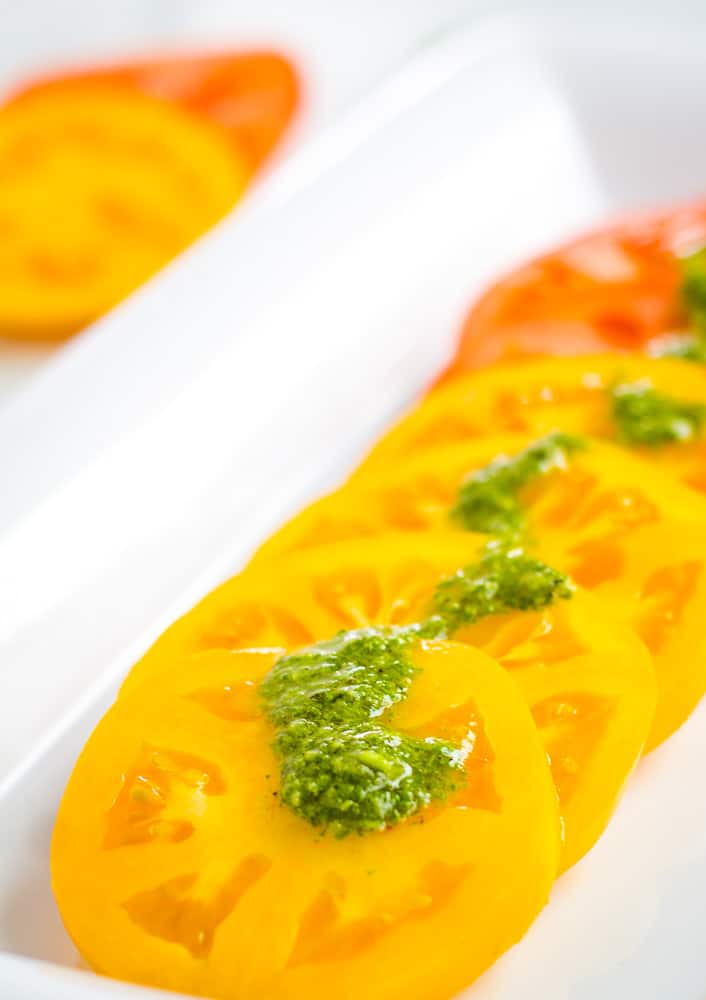 sliced tomato with basil sauce overtop