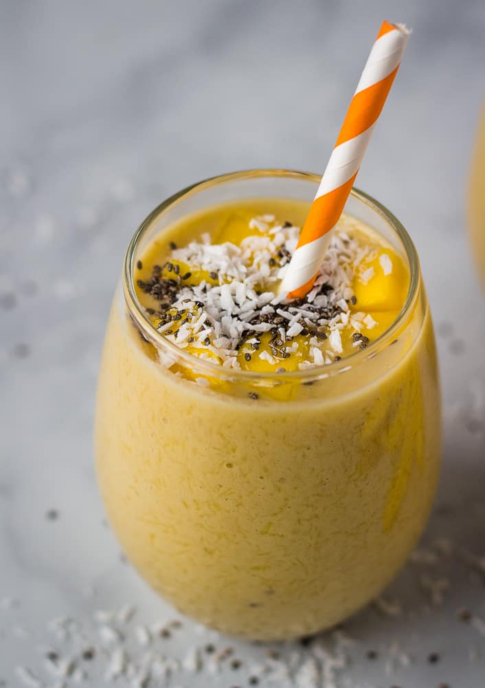 mango smoothie in glass cup with orange straw