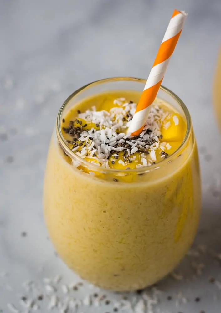 mango smoothie in glass cup with orange straw