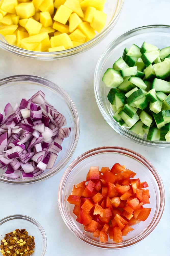 cucumber, mango, onion, and red pepper diced in glass bowls