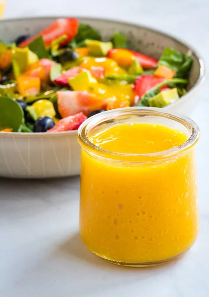 mango dressing in glass jar with salad in background