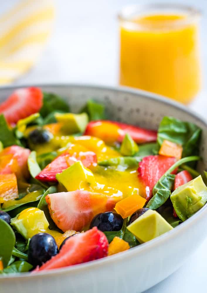 close up of berry salad with mango dressing in background