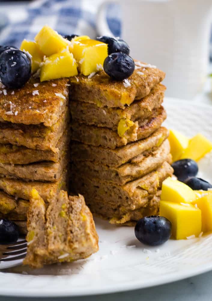 stack of mango pancakes with a bite o pancake on a fork