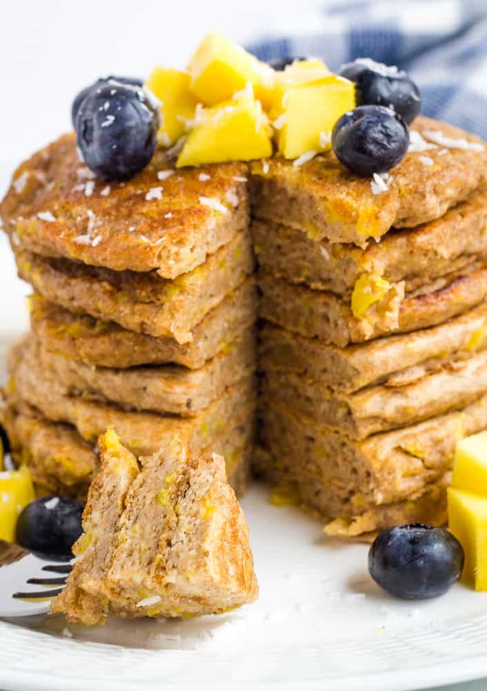 stack of mango pancakes topped with blueberries and mango