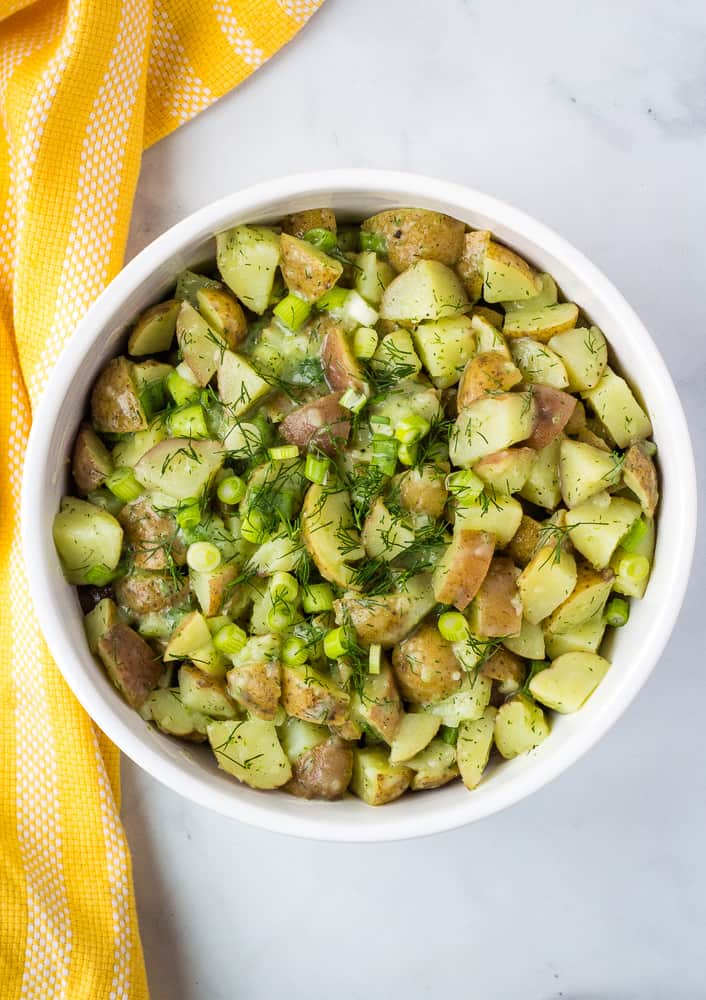 vegan potato salad with fresh herbs in white bowl