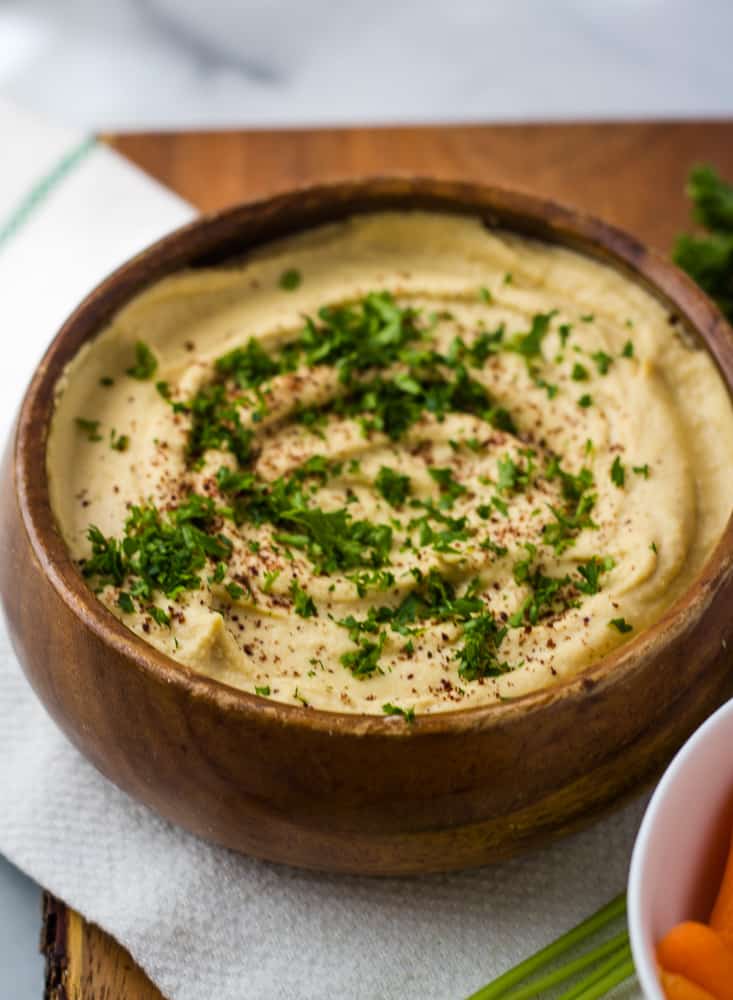 hummus in wood bowl topped with sumac and parsley