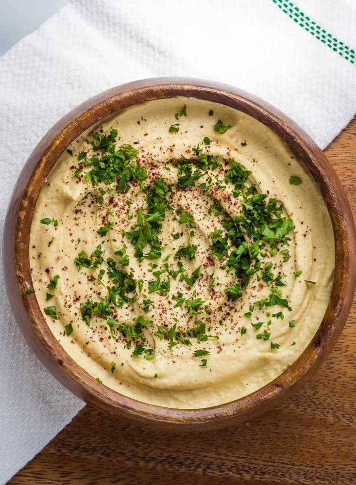 gluten free hummus in brown bowl topped with parsley