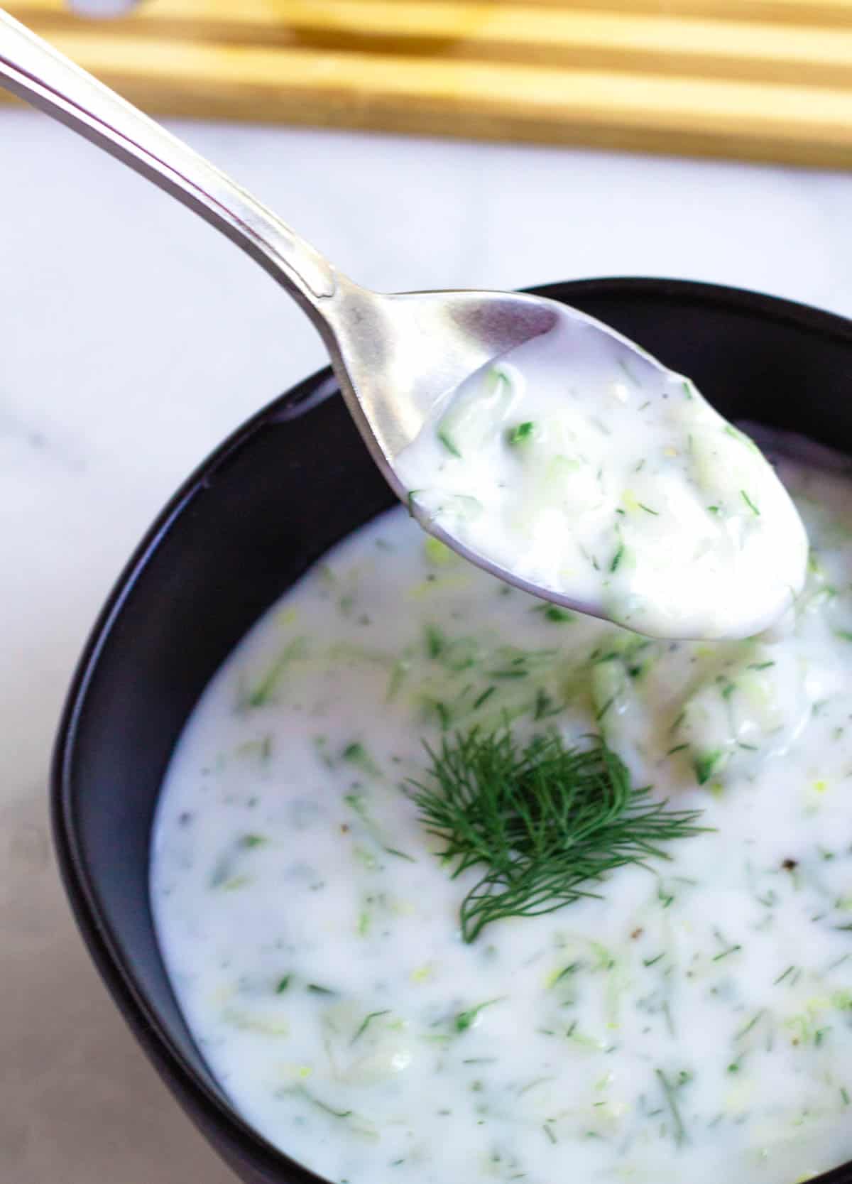 spoon dipped in bowl of tzatziki