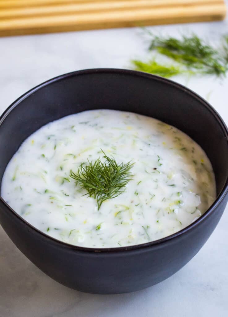 vegan tzatziki topped with dill in black bowl