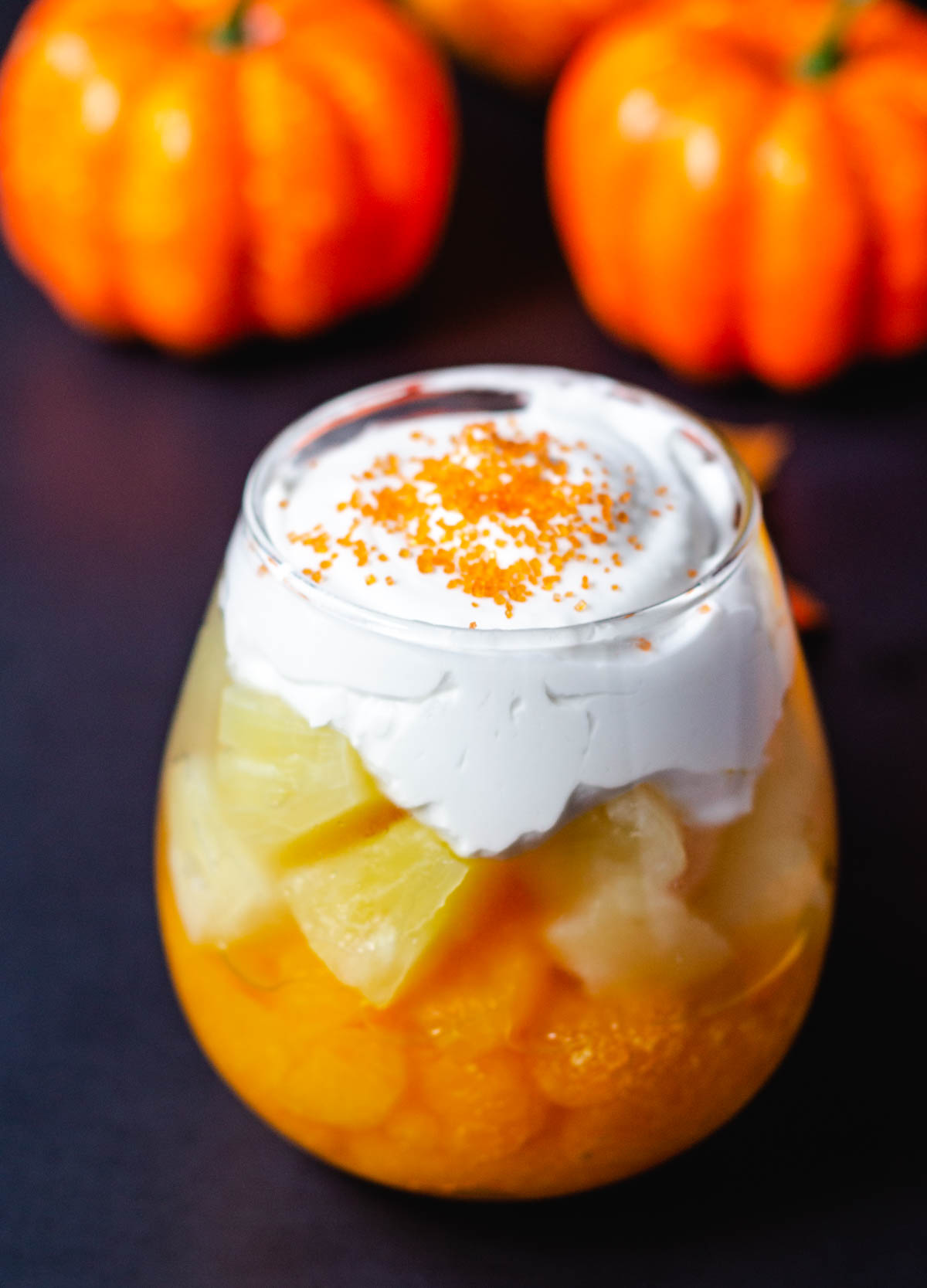 Fruit cups with oranges and pineapple topped with whipped cream.