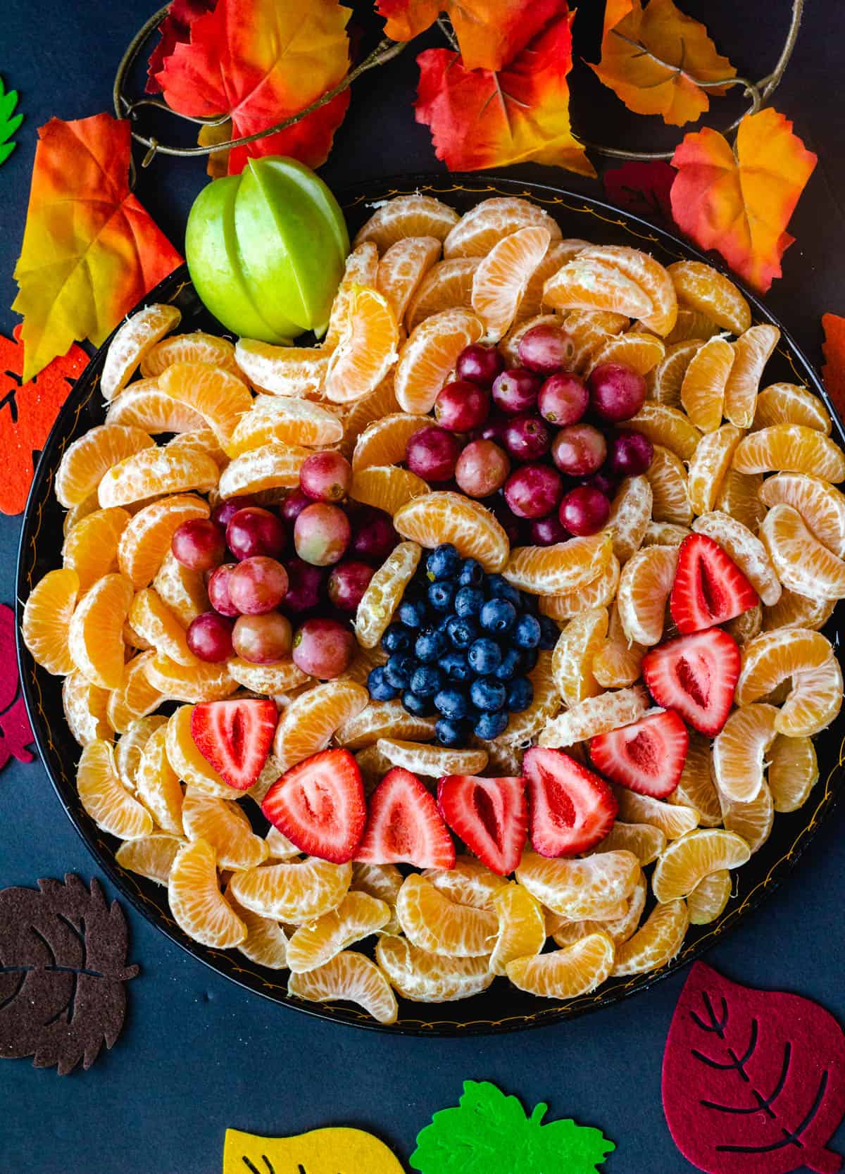 jack-o-lantern fruit tray with oranges, berries, and grapes